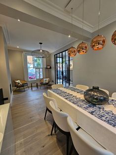 the dining room table is set with white chairs and blue patterned cloth on top of it