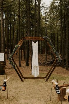 a wedding dress hanging on a wooden frame in the woods