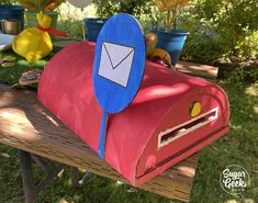 a red mailbox sitting on top of a wooden table