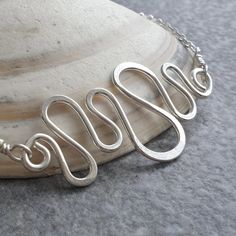 This sterling silver wave bracelet is made from heavy gauge sterling wire, formed into waves and curves of different sizes. I have lightly hammered the tops of the curves for strength and added the wave section to sterling silver belcher chain. The bracelet has been given a brightly polished finish and fastens with a lobster clasp.  The wavy chain bracelet makes a lovely piece of coastline inspired jewellery which would make a fab gift for any beach lover or fan of geometric jewelry. Length: 7 1 Wave Inspired Jewellery, Wave Bracelet, Belcher Chain, Wave Necklace, Beach Lover, Geometric Jewelry, Beach Lovers, Chain Link Bracelet, Bracelet Gift