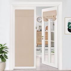 an open door leading to a living room with potted plants and pictures on the wall