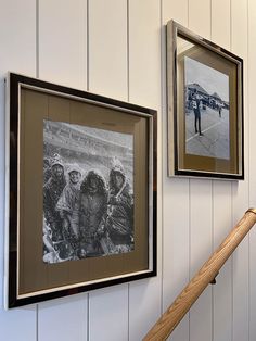 two framed photographs hang on the wall next to a baseball bat