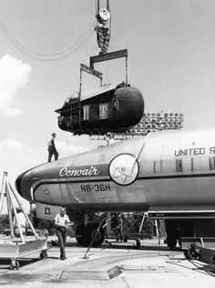 an airplane being lifted by a crane on top of it's nose in black and white