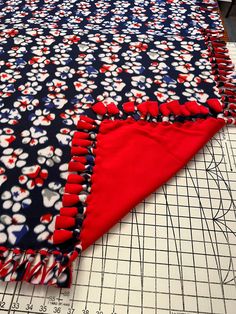 a piece of cloth with red, white and blue flowers on it sitting on a cutting board