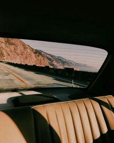 the view from inside a car looking at mountains in the distance and on the road