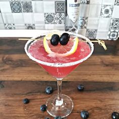 a red drink with black olives on the rim