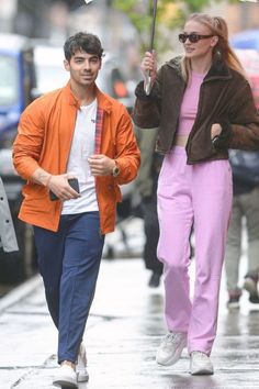 a man and woman walking down the street under an umbrella