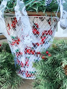 a basket filled with pine cones and candy canes on top of a table next to evergreen branches