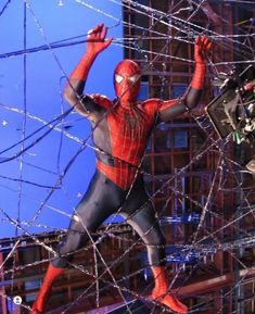 a spider man is standing in the middle of a web - covered area with his hands up