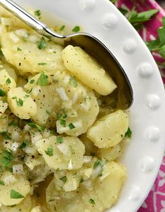 a white bowl filled with pasta and garnished with parsley next to a spoon