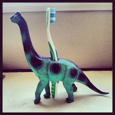 a toy dinosaur with a toothbrush in it's mouth and the caption says, drill a hole through a plastic toy to create a fun toothbrush holder