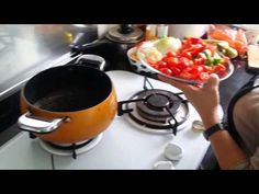 a woman holding a bowl full of food on top of a stove next to an oven