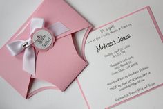 a pink and white wedding card with a bow on the front, and an envelope in the back