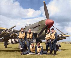 the men are posing in front of an old airplane