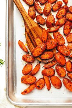 cooked carrots on a baking sheet with a wooden spoon