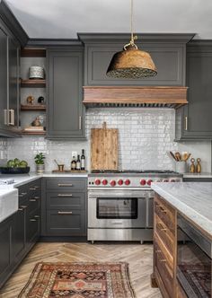 a kitchen with gray cabinets and an area rug in front of the stove top oven