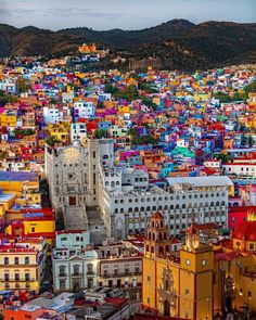 colorful buildings are in the middle of a large city with mountains in the back ground