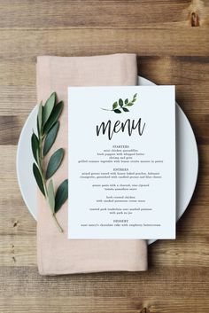 a menu card on top of a plate next to a fork and knife with leaves