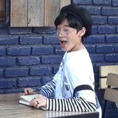 a young boy sitting at a table with a book in front of him and his mouth open