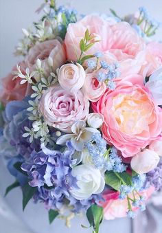 a bridal bouquet with pink, blue and white flowers in it's centerpiece