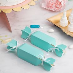 two blue boxes tied with white ribbon on a table next to flowers and other items