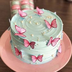 a blue cake with pink butterflies on it sitting on a plate next to candy sticks