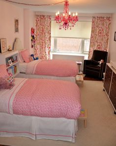 two twin beds in a bedroom with pink bedding and chandelier hanging from the ceiling