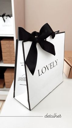 a white bag with a black bow on the front that says lovely and sits on a table