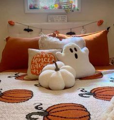 a bed topped with lots of pillows covered in pumpkins and ghost decorations on top of it