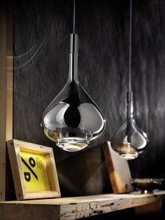 three hanging lights in a room with black walls and wood flooring, one light has an award plaque on it