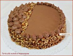 there is a chocolate cake with nuts on the top and bottom, sitting on a white plate