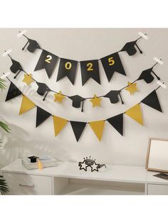 black and gold graduation decorations hanging on the wall in front of a desk with a computer