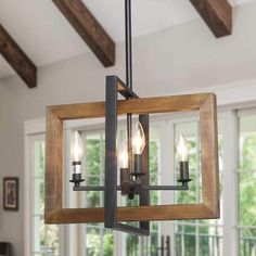 a chandelier hanging from the ceiling in a room with wood beams and windows