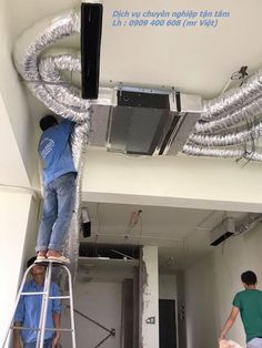 two men working on a ceiling fan in a room that is being renovated with duct tape