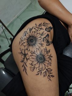 a woman's thigh with sunflowers and butterflies on it