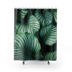 a shower curtain with green leaves on the outside and black inside, in front of a white background