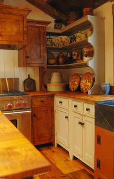 an old fashioned kitchen with wooden cabinets and counter tops is pictured in this image, there are dishes on the shelves above the sink