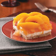 a piece of dessert on a red plate with silverware and napkins in the background