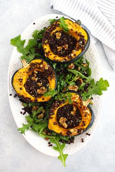 a white plate topped with stuffed acorns covered in black lentils and greens