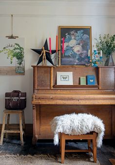 a room with a piano, stool and pictures on the wall