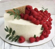 a cake decorated with raspberries and an ice cream cone