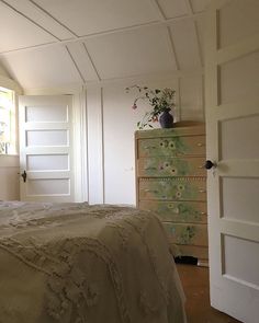 a bedroom with a bed, dresser and flower pot on top of the headboard