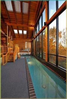 an indoor swimming pool in the middle of a room with large windows and wood trimmings