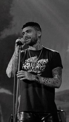 a man with tattoos on his arm holding a microphone and standing in front of a stage