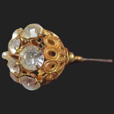 This sparkling hatpin is ready to be worn and admired! A lovely example dating from the Victorian / Edwardian era. From top to bottom it measures 4 inches long. The pierced gold gilt frame measures 6/8 of an inch wide. Gilt is holding up beautifully as are the glistening paste stones. In the right lighting they come alive! Largest ones have an average width of 6.25mm, smaller ones 4.50mm. The top is finished off with a faux pearl. All rhinestones are in place and held securely. Top pearl shows a Heirloom Gold Evening Brooches, Heirloom Gold Brooches For Evening, Victorian Gold Brooch For Wedding, Victorian Gold Brooches For Evening, Victorian Gold Wedding Brooch, Ornate Gold Brooches For Vintage Events, Antique Gold Brooches For Wedding, Ornate Gold Brooches For Evening, Victorian Gold Brooch With Screw Back