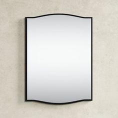 a mirror mounted to the side of a wall with a black frame and curved edge