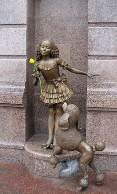 a statue of a girl holding a flower next to a dog