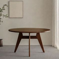 a wooden table sitting in front of a window next to a vase filled with flowers