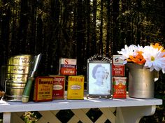 there are many tins on the table with flowers next to them and an old photo