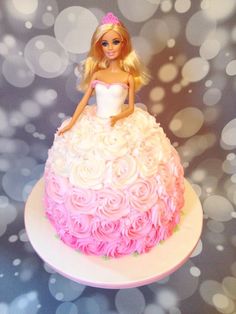 a barbie doll cake with pink and white frosting on the top, sitting on a plate